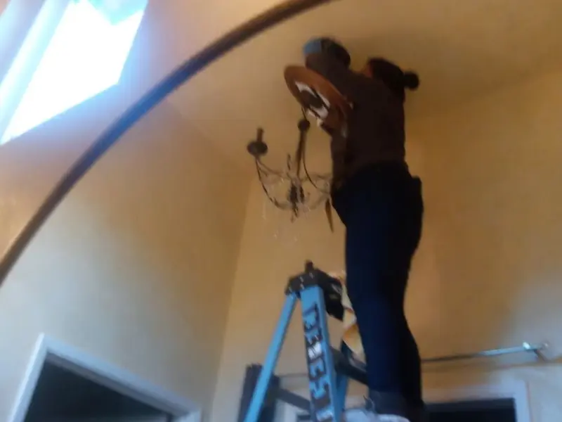 Electrician installing a chandelier in a Fox Farm-College residence